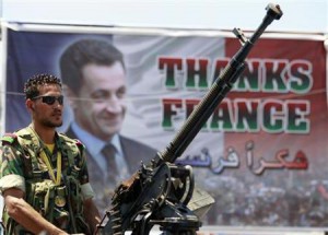 Libyan rebel fighters poses in front of Nicolas Sarkosy